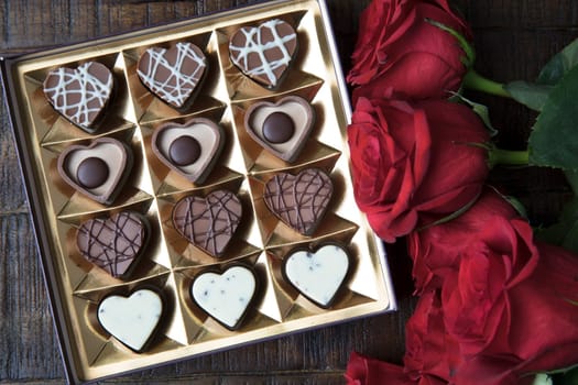 Box of romantic heart shaped chocolates and red roses.