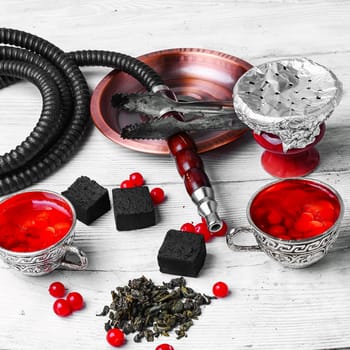Turkish hookah and tea with berries on stone background
