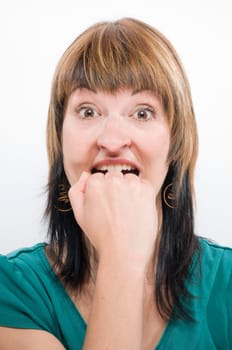 Head portrait of a young brunette woman against a white background,desperately biting her fist.