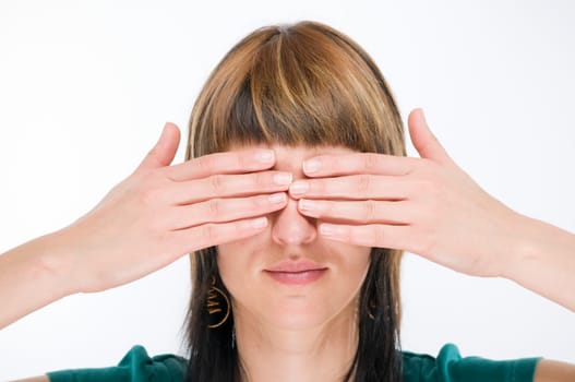 Head portrait of a young brunette woman against a white background holding her eyes.