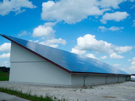 Sloping and lateral view of a modern agricultural building with complete photovoltaic roofing.