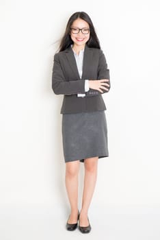 Portrait of young Asian female business people in formalwear smiling, full body standing on plain background.