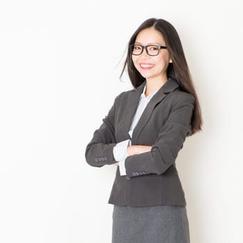 Portrait of Asian businesspeople in formalwear smiling and looking at camera, standing on plain background.