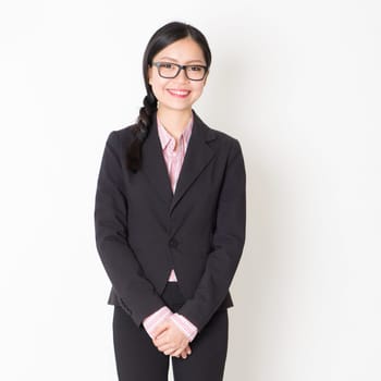 Portrait of Asian business people in formalwear smiling and looking at camera, standing on plain background.