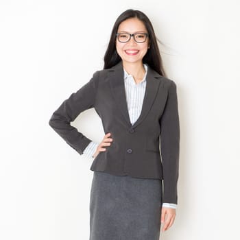 Portrait of young Asian business people in formalwear smiling and looking at camera, standing on plain background.