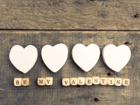 Wooden dices with heart shapes on a rustic wooden background, vintage color toned love concept image