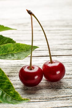 Cherries with green leaves on wooden background
