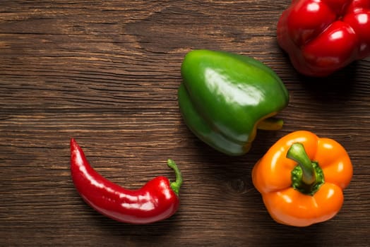 Green, yellow and red bell pepper on wooden background