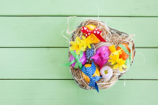 Hearty basket with colourful eggs and flowers for Easter