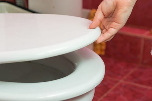 Child's hand puts the toilet seat