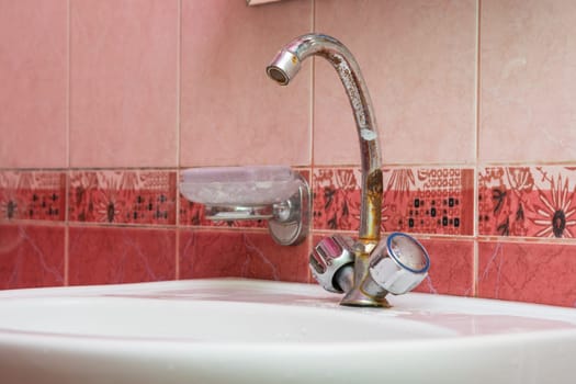 Wash basin mounted with a rusty crane