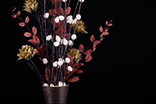 Flower arrangement in a vase with warm dark tones on a black background