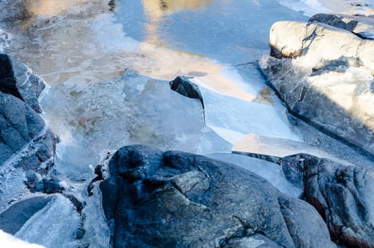some ice on the water and rocks and stone