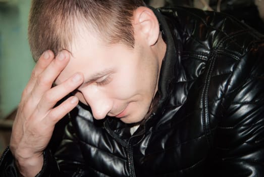 Portrait of the thoughtful young man with a hand at a forehead