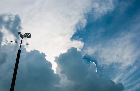 Weather vane against the evening sky and clouds