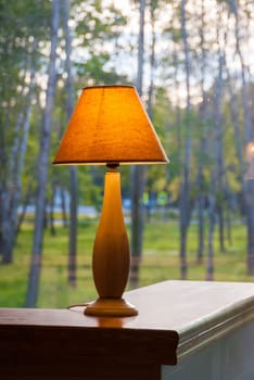 Burning table lamp in front of the window