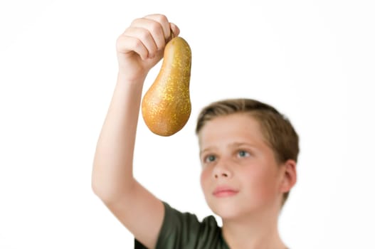 Frontal head and shoulder view of a young male teenager against a white background with his right hand holding up a pear in front of him