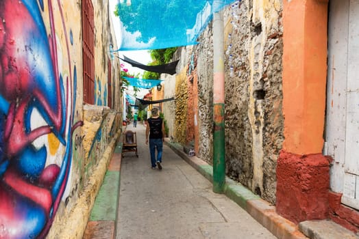 CARTAGENA, COLOMBIA - MAY 24: People walk through a narrow alley in the Getsemani neighborhood in Cartagena, Colombia on May 24, 2016
