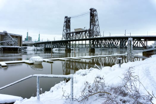 Snow covered boat on the Willamette River with the Steel Bridge in the background in Portland, Oregon