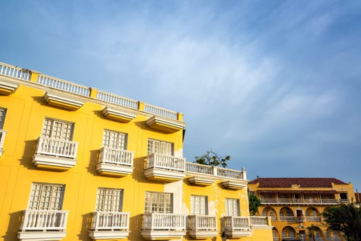 Yellow colonial building with white balconies in the historic old city center of Cartagena, Colombia