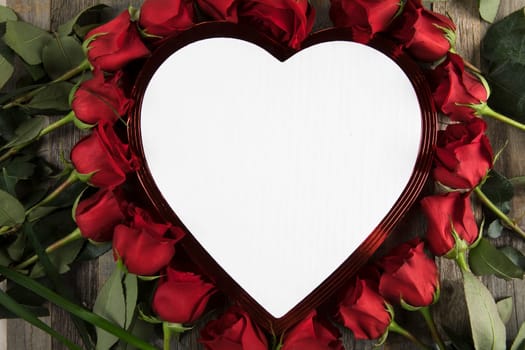 Romantic red roses surrounding heart shaped chocolate box with white copy space.