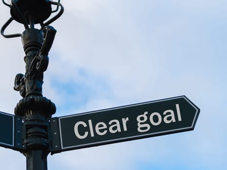 Street lighting pole with conceptual message Clear Goal on directional arrow over blue cloudy background.