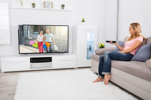 Young Happy Woman Sitting On Couch Watching Romantic Movie On Television At Home