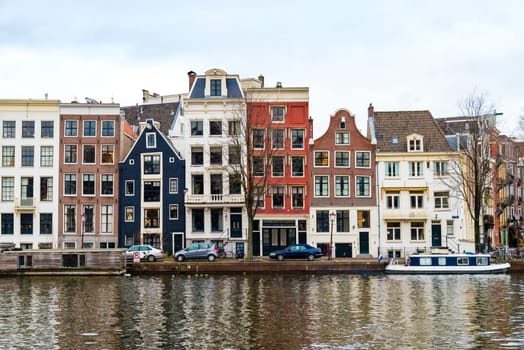 Amsterdam, Netherlands - January 9, 2017: Street view with traditional Dutch row houses and famous canals in Amsterdam historical city center, the Netherlands’ capital, known for its artistic heritage