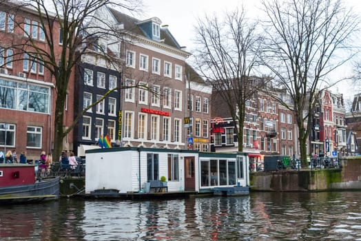 Amsterdam, Netherlands - January 9, 2017: Street view with traditional Dutch row houses and famous canals in Amsterdam historical city center, the Netherlands’ capital, known for its artistic heritage