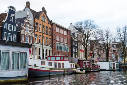 Amsterdam, Netherlands - January 9, 2017: Street view with traditional Dutch row houses and famous canals in Amsterdam historical city center, the Netherlands’ capital, known for its artistic heritage