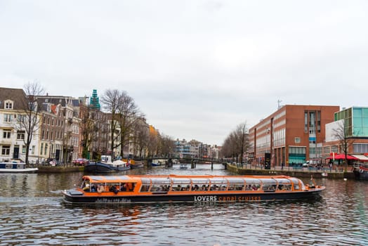 Amsterdam, Netherlands - January 9, 2017: Street view with traditional Dutch row houses and famous canals in Amsterdam historical city center, the Netherlands’ capital, known for its artistic heritage