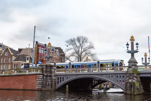 Amsterdam, Netherlands - January 9, 2017: Street view with traditional Dutch row houses and famous canals in Amsterdam historical city center, the Netherlands’ capital, known for its artistic heritage