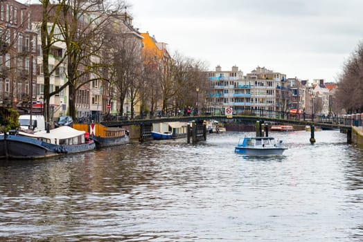 Amsterdam, Netherlands - January 9, 2017: Street view with traditional Dutch row houses and famous canals in Amsterdam historical city center, the Netherlands’ capital, known for its artistic heritage