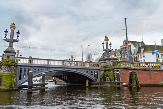 Amsterdam, Netherlands - January 9, 2017: Street view with traditional Dutch row houses and famous canals in Amsterdam historical city center, the Netherlands’ capital, known for its artistic heritage