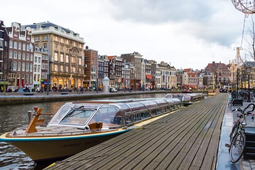 Amsterdam, Netherlands - January 9, 2017: Street view with traditional Dutch row houses and famous canals in Amsterdam historical city center, the Netherlands’ capital, known for its artistic heritage