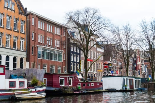 Amsterdam, Netherlands - January 9, 2017: Street view with traditional Dutch row houses and famous canals in Amsterdam historical city center, the Netherlands’ capital, known for its artistic heritage