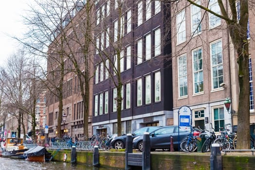 Amsterdam, Netherlands - January 9, 2017: Street view with traditional Dutch row houses and famous canals in Amsterdam historical city center, the Netherlands’ capital, known for its artistic heritage