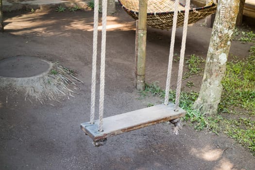 Empty wooden swing in the garden, stock photo