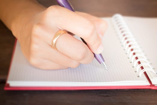 Woman hand writing on noteboook paper, stock photo