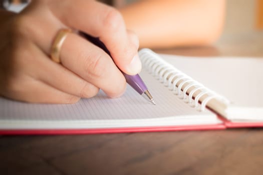 Woman hand writing on noteboook paper, stock photo