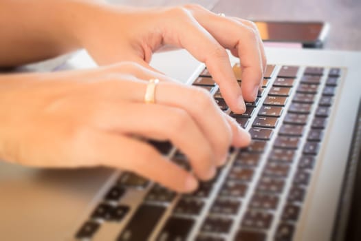 Typing on keyboard laptop at work table, stock photo