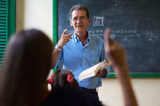 Young people and education. Group of hispanic students in class at school during lesson. Girl raising hand and asking question to teacher
