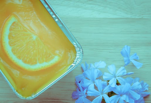 Orange soft cake with sliced orange fruit in aluminum foil tray on wooden background. Retro-Vintage filter effect