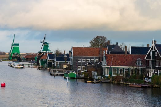 Zaanse Schans, Netherlands - January 10, 2017: Rural Dutch scenery with water canals in Zaanse Schans village known for well-preserved historic windmills and row houses near Amsterdam, Netherlands.