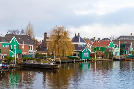 Zaanse Schans, Netherlands - January 10, 2017: Rural Dutch scenery with water canals in Zaanse Schans village known for well-preserved historic windmills and row houses near Amsterdam, Netherlands.