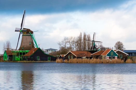 Zaanse Schans, Netherlands - January 10, 2017: Rural Dutch scenery with water canals in Zaanse Schans village known for well-preserved historic windmills and row houses near Amsterdam, Netherlands.