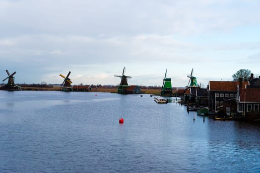 Zaanse Schans, Netherlands - January 10, 2017: Rural Dutch scenery with water canals in Zaanse Schans village known for well-preserved historic windmills and row houses near Amsterdam, Netherlands.