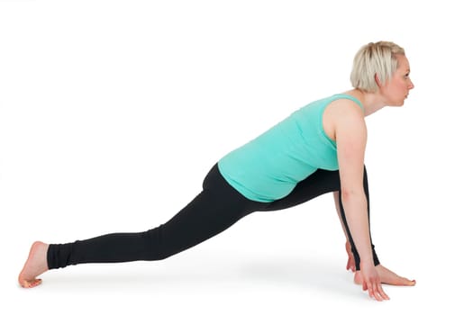 Full-body view of a young blonde woman doing yoga exercises against a white background with a slight shadow