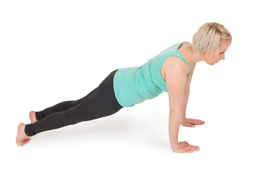 Full body view of a young blonde woman during yoga exercise "Cobra"" Step1 against a white background with a slight shadow."