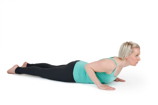Full-body view of a young blonde woman during the yoga exercises "Cobra"" against a white background with a slight shadow"